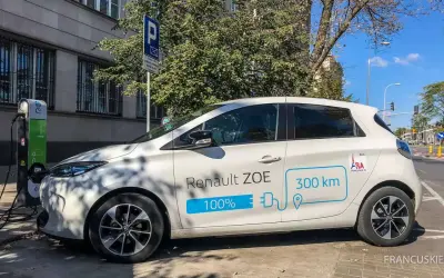 Biały Renault ZOE ładuje się na stacji. Czy samochód elektryczny się opłaca? Zasięg 300 km sugeruje, że tak.