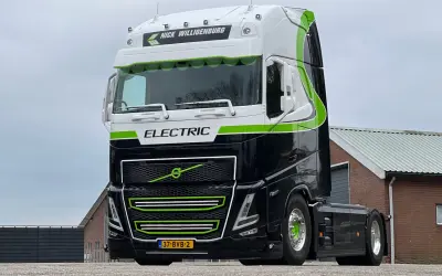 Nowoczesna, czarna elektryczna ciężarówka z zielonymi akcentami i napisem "ELECTRIC" gotowa do drogi.