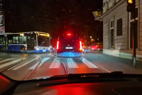 Nocne miasto, tramwaje i samochody. Nagłe hamowanie przepisów ruchu drogowego, gdy kierowca widzi czerwone światło.