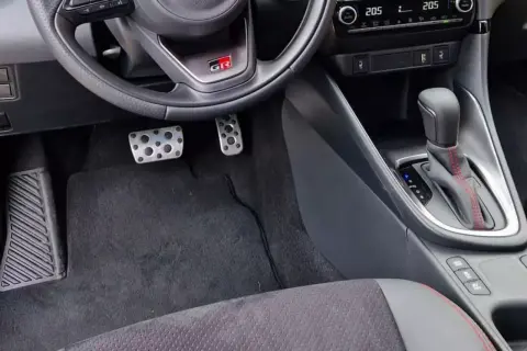Wnętrze samochodu z pedałami i dźwignią zmiany biegów. Wybór między automat a manual jest widoczny.