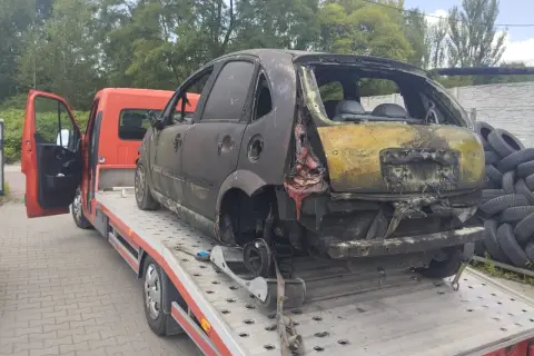 Spalony samochód na lawecie, gotowy do złomowania. Może to być początek drogi po dopłatę za złomowanie starego samochodu.