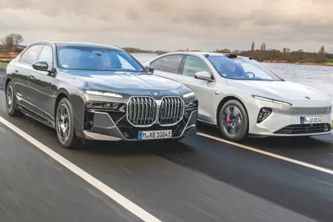 Dwa nowoczesne sedany, w tym chińskie BMW, pędzą po mokrej drodze.
