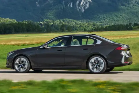 Ciemny sedan BMW jedzie przez malowniczy krajobraz. Idealny do biznesu, gdy rozważasz odliczenie VAT od leasingu samochodu osobowego powyżej 150 tys.