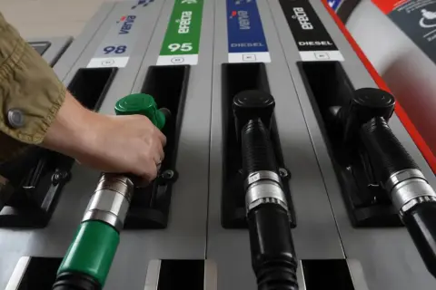 Ręka sięga po zieloną dyszę dystrybutora, obok czarne dysze do **diesel paliwo jak wygląda**.