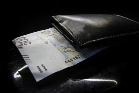 Czarny portfel z banknotem 500 zł. Zastanawiasz się nad opłatami dodatkowymi w leasingu a VAT?