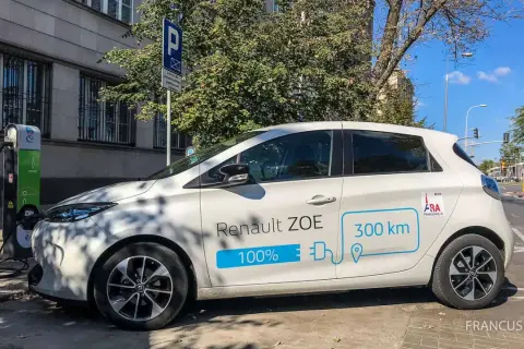 Biały Renault ZOE ładuje się na stacji. Czy samochód elektryczny się opłaca? Zasięg 300 km sugeruje, że tak.