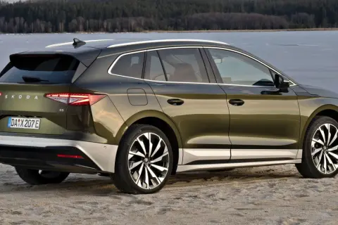Zielony Skoda Enyaq na plaży, z widokiem na zamarznięte jezioro. Poznaj skoda enyaq wymiary i jego przestronne wnętrze.