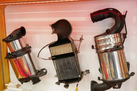 Trzy części samochodowego katalizatora, pokazujące jego budowę: metalową obudowę i ceramiczny wkład.
