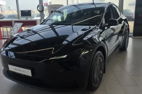 Błyszczący, czarny Tesla Model Y, idealny dla siedmioosobowej rodziny, stoi w salonie.