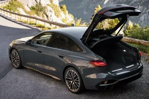 Szary Audi RS 6 Avant, czyli liftback co to, z otwartym bagażnikiem na górskiej drodze.