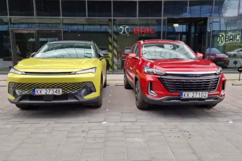 Dwa nowe chińskie samochody, żółty i czerwony, zaparkowane przed salonem BAIC w Europie.