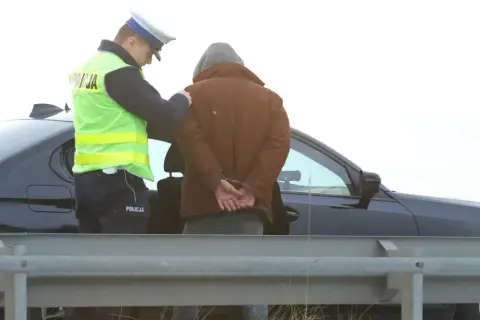Policjant zakłada kajdanki zatrzymanemu mężczyźnie. Nowelizacja kodeksu karnego w praktyce.