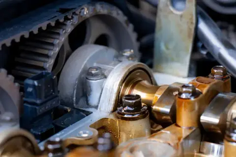 Widok na mechanizm rozrządu w aucie: pasek zębaty, koła zębate i wałek rozrządu.
