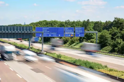 Autostrada w Niemczech, znaki drogowe wskazujące kierunki miast. Uważaj na odsetki za niezapłacony mandat w Niemczech, bo mogą Cię dogonić jak te ciężarówki.