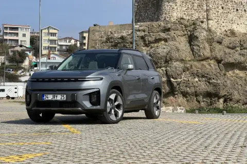 Nowy SsangYong elektryczny SUV stoi na parkingu przed kamiennym murem.