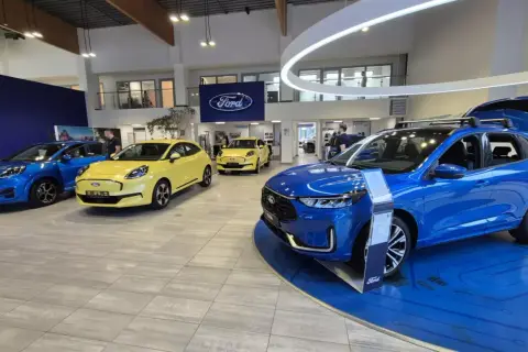Salon Forda z kilkoma nowymi autami, w tym niebieskim SUV-em. Zastanawiasz się, auto w leasingu co to znaczy? To opcja dla Ciebie!