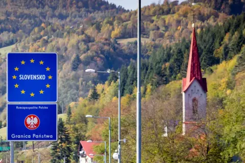 Granica Słowacji i Polski. W tle jesienne wzgórza i wieża kościoła. Fotoradary słowacja pilnują porządku.