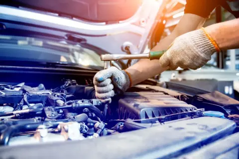 Mechanik dokręca śrubę w silniku. Silentblock to element amortyzujący drgania, kluczowy dla komfortu jazdy.