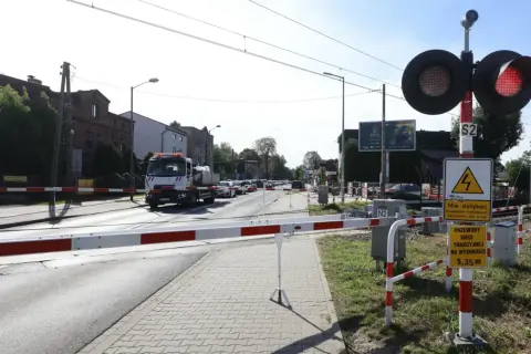 Przejazd kolejowy z opuszczonymi rogatkami i czerwonymi światłami. Kierowca ciężarówki może otrzymać mandat za przejazd kolejowy, jeśli zignoruje sygnały.