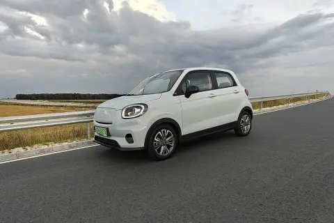 Biały samochód elektryczny na drodze, symbol rosnącej liczby aut elektrycznych w Polsce.
