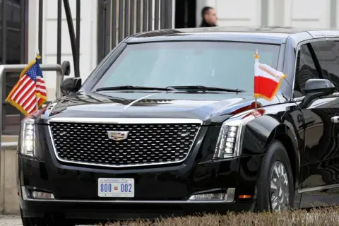 Czarne auto prezydenta USA, Cadillac Escalade, z flagami USA i Polski.