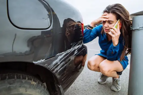 Zmartwiona kobieta dzwoni po pomoc po tym, jak jej auto w leasing ucierpiało w wyniku szkody z OC sprawcy.