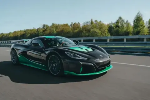 Czarny, sportowy, chorwackie auto elektryczne z zielonymi akcentami pędzi po torze wyścigowym.