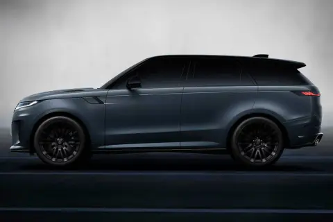 Elegancki, ciemnoszary land rover elektryczny z czarnymi felgami, poruszający się po ciemnej drodze.
