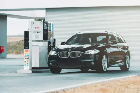 Czarne BMW na stacji paliw. Przykład, jak odliczyć 50% VAT od paliwa, może być związany z kosztami podróży służbowych.