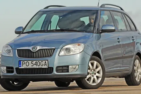 Niebieska Skoda Fabia Combi, idealne jakie auto rodzinne, z kierowcą za kierownicą, na tle jasnego nieba.