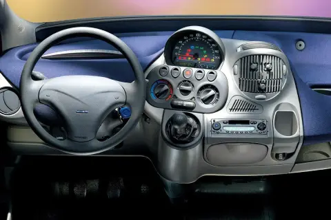 Widok na **fiat multipla wnętrze**: kierownica, deska rozdzielcza z radiem i nawiewami, dźwignia zmiany biegów.