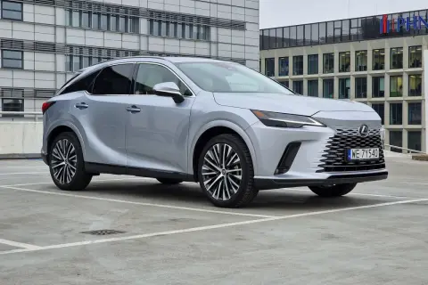 Eleganckie japońskie samochody, jak ten srebrny Lexus, prezentują się nowocześnie na tle biurowców.