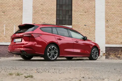 Czerwony kombi Ford Focus, elegancki i sportowy, zaparkowany przy ceglanej ścianie.