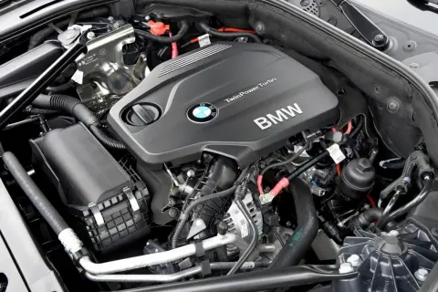 Silniki BMW F10 TwinPower Turbo. Widok na czarny, nowoczesny silnik z logo BMW i licznymi przewodami.