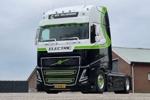 Nowoczesna, czarna elektryczna ciężarówka z zielonymi akcentami i napisem "ELECTRIC" gotowa do drogi.