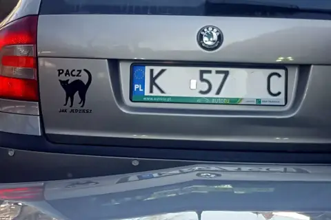 Czarny kot na klapie bagażnika z napisem "PACZ JAK JEDZIESZ". Tablica rejestracyjna K 57 C.