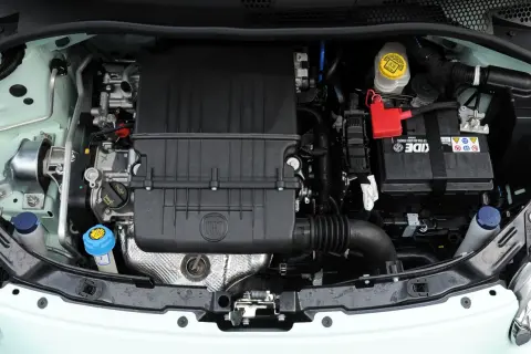 Silniki Fiata 500 w komorze silnika. Widoczny czarny plastikowy element z logo FIAT, akumulator i płyny eksploatacyjne.