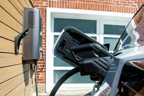 Ładowanie samochodu elektrycznego. Stacja ładująca podłączona do pojazdu, magazyn energii z samochodu elektrycznego gotowy do pracy.