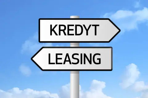 Znak drogowy z napisami "KREDYT" i "LEASING" pod niebieskim niebem z chmurami. Wybór między finansowaniem a zdolnością kredytową.
