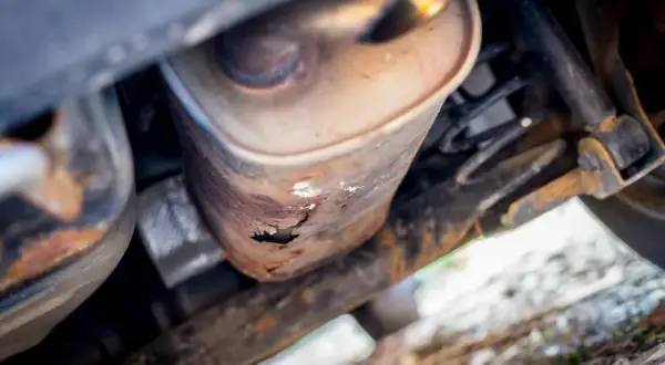 Widok od spodu na skorodowany tłumik Passata B6. Rdza przeżarła metal, tworząc dziury.