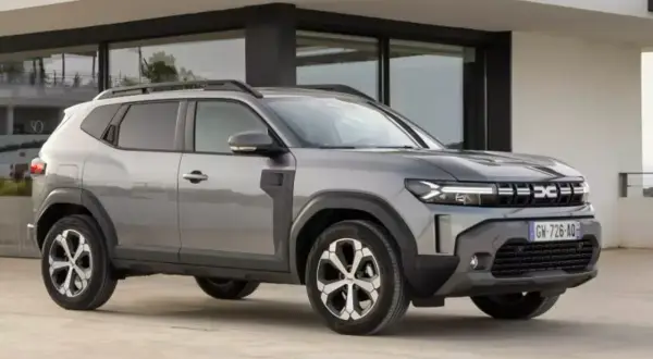 Szary Dacia Duster, jeden z najlepszych aut do gazu, parkuje przed nowoczesnym budynkiem.