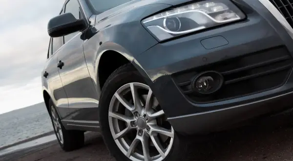 Duże auto terenowe z błyszczącym lakierem stoi przy wodzie.
