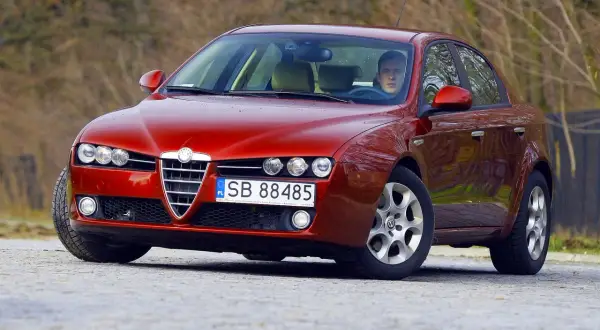 Czerwone Alfa Romeo 159 z kierowcą. Zastanawiasz się, jaki silnik ma to Alfa Romeo 159?