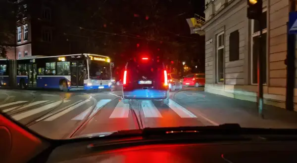 Nocne miasto, tramwaje i samochody. Nagłe hamowanie przepisów ruchu drogowego, gdy kierowca widzi czerwone światło.
