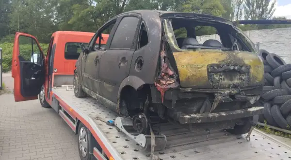 Spalony samochód na lawecie, gotowy do złomowania. Może to być początek drogi po dopłatę za złomowanie starego samochodu.