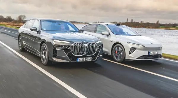 Dwa nowoczesne sedany, w tym chińskie BMW, pędzą po mokrej drodze.