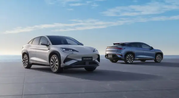 Dwa nowoczesne SUV-y marki BYD, jedne z wielu chińskich marek samochodów, prezentują się na tle błękitnego nieba i morza.