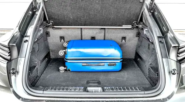 Bagażnik Porsche Macan, z niebieską walizką, pokazuje, jak kompaktowe są jego wymiary.