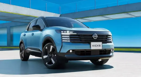 Niebieski Nissan Kicks, segment B, prezentuje się nowocześnie na tle betonowej konstrukcji i błękitnego nieba.