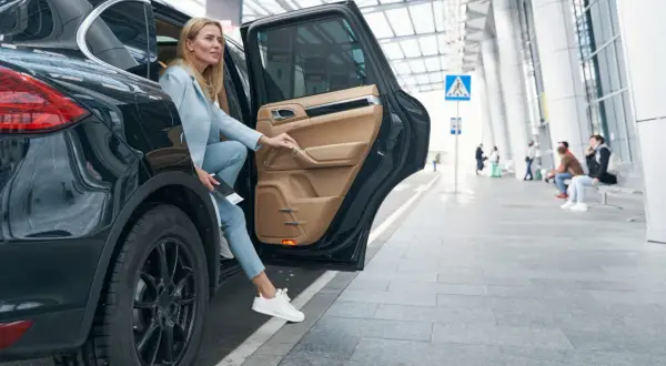 Kobieta wysiada z czarnego SUV-a. Zastanawia się, czy ubezpieczenie samochodu 75 czy 100 w koszty będzie lepsze.